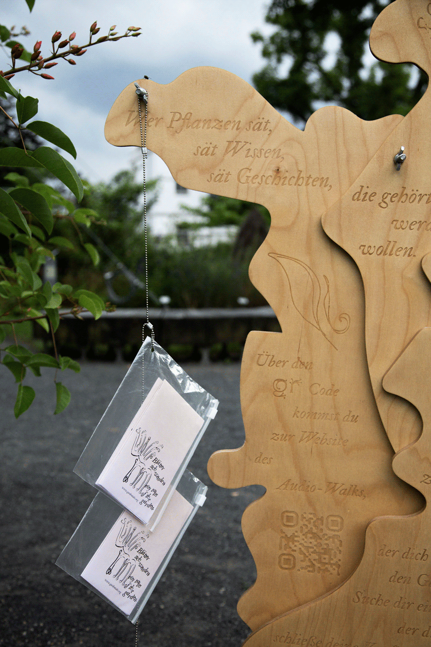 Woodensculpture with engraved type and two broschures with text hanging from the sculpture